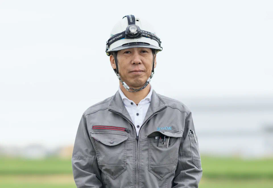 ヘルメットと作業着を着用した社員 A.Hのポートレート