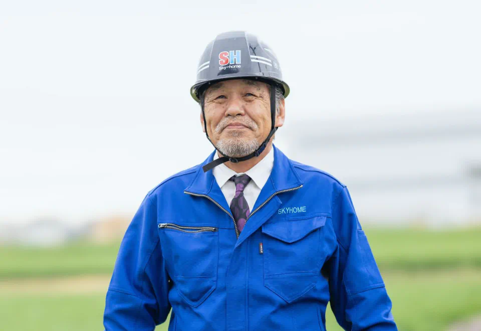 ヘルメットと青い作業着を着用した社員 K.Yのポートレート