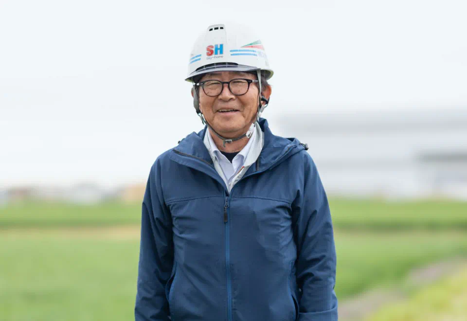 ヘルメットと青い上着を着用した社員 T.Aのポートレート